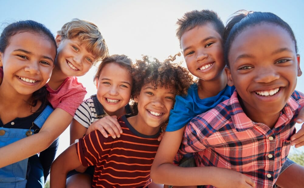 six young children gathered around each other smiling outside