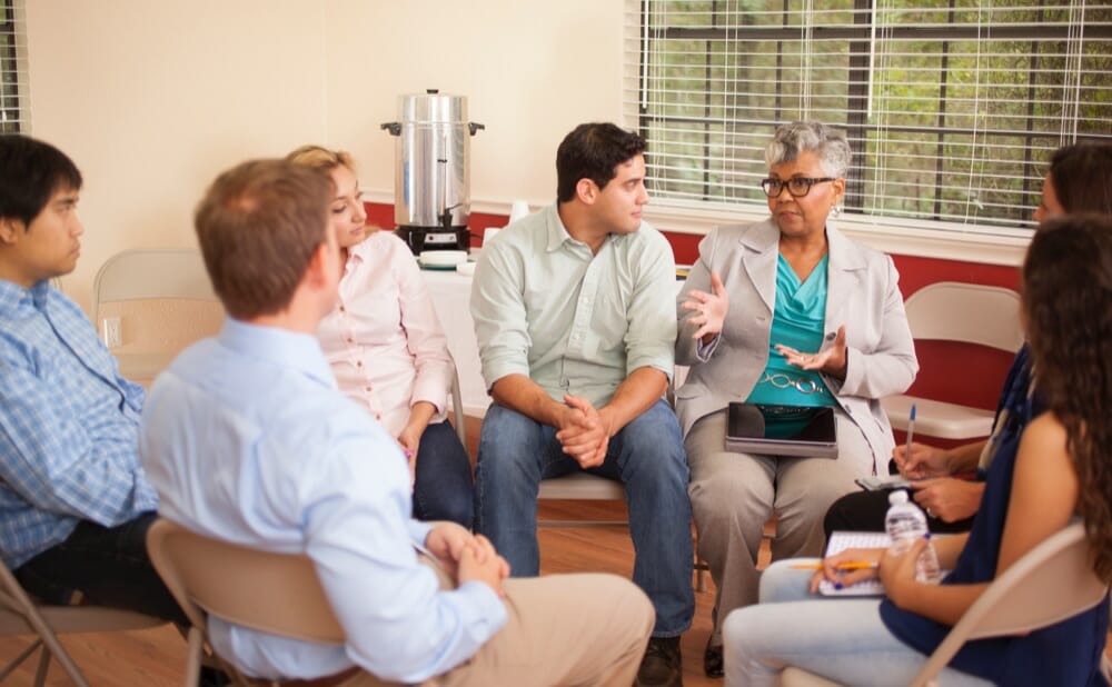 an older african american woman speaking out at an addiction treatment meeting