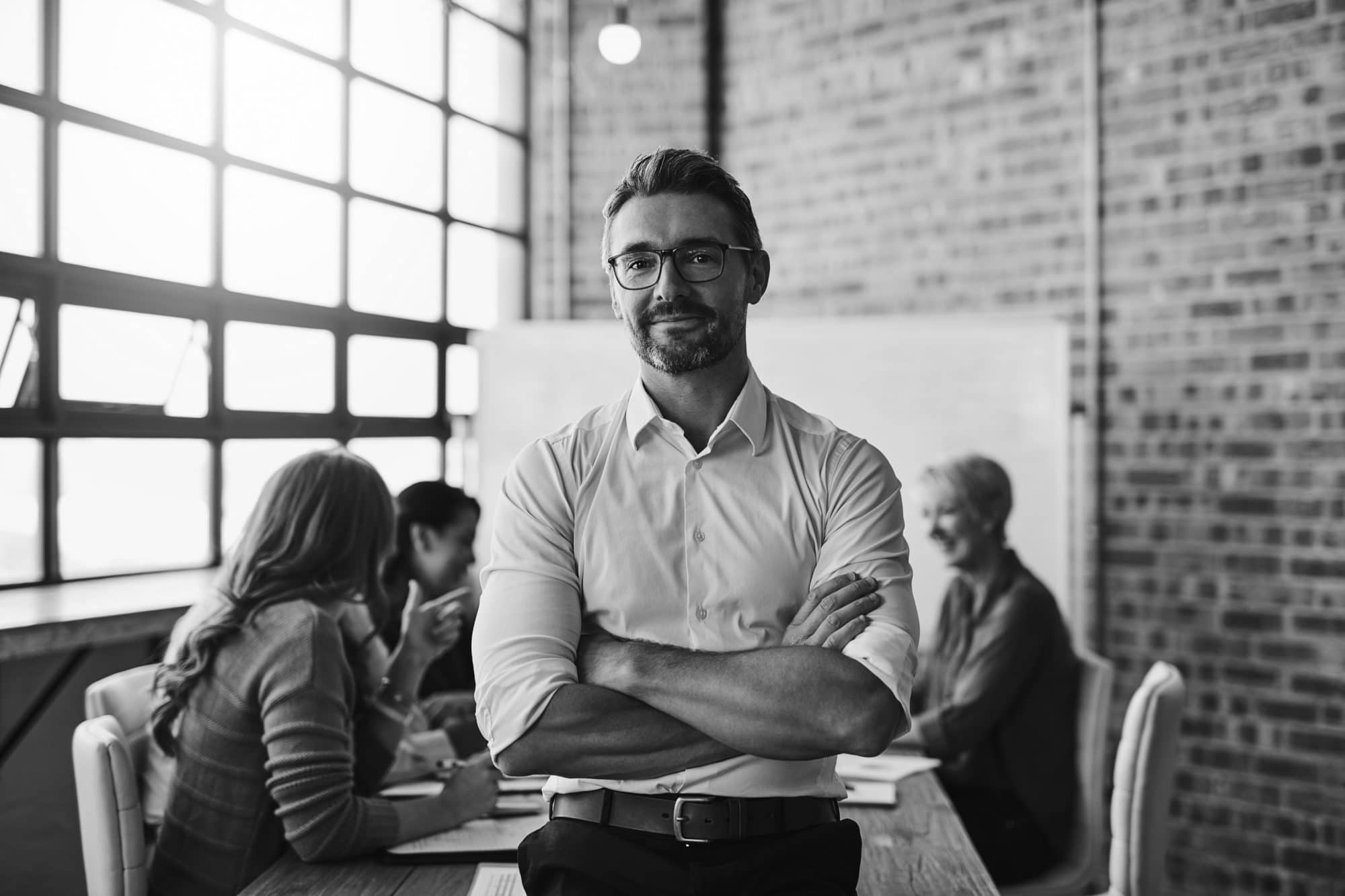 Cropped shot of a businessman standing in the office with his arms folded looking confident and smiling at the camera
