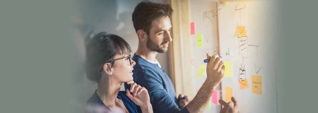 image of a man drawing out EHR implementation tips on a white board with a woman beside him