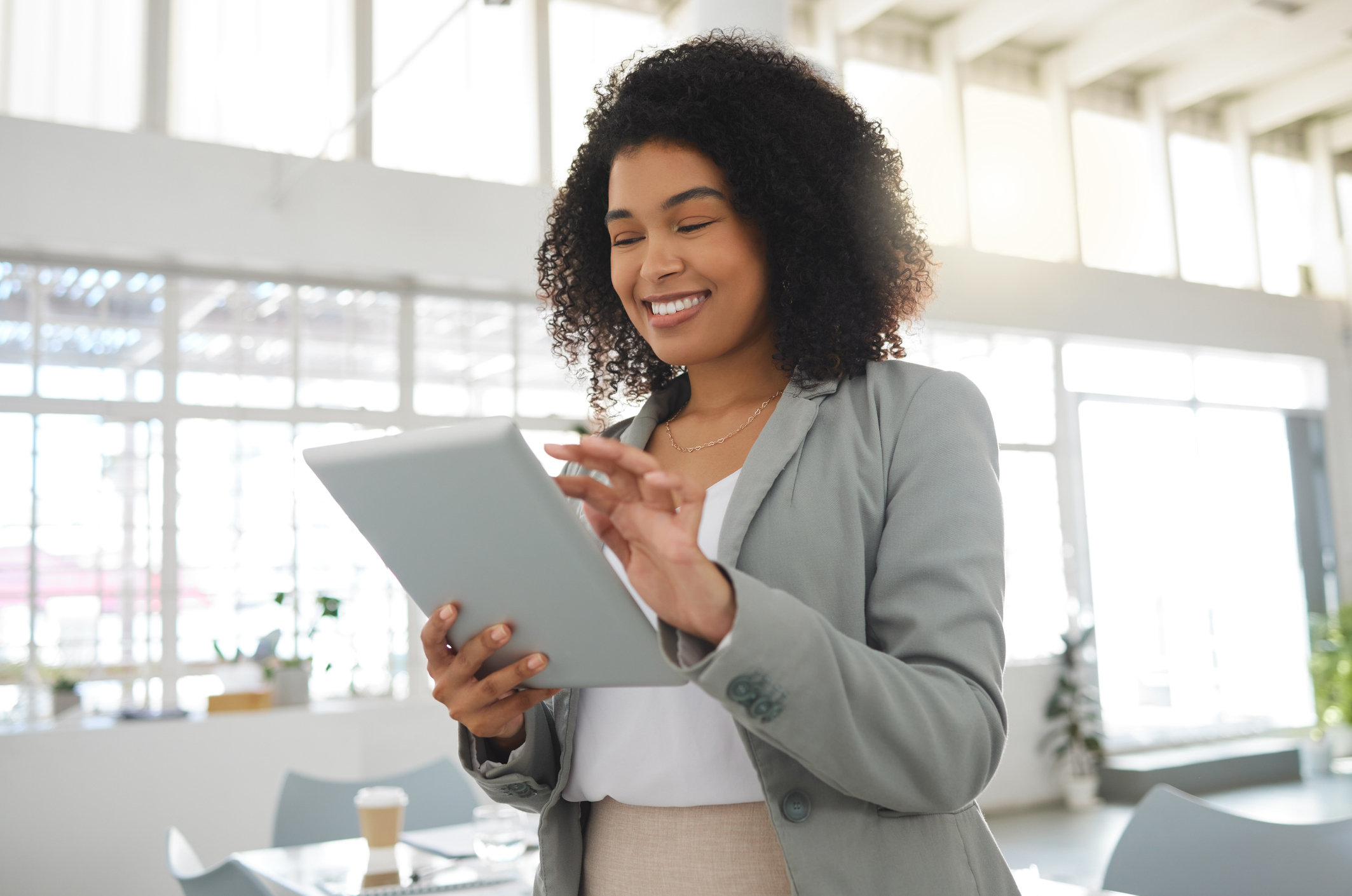 businesswoman working on a digital tablet in an office. One cheerful hispanic female boss with a curly afro holding and using social media on a digital tablet at work in Merced County Behavioral Health