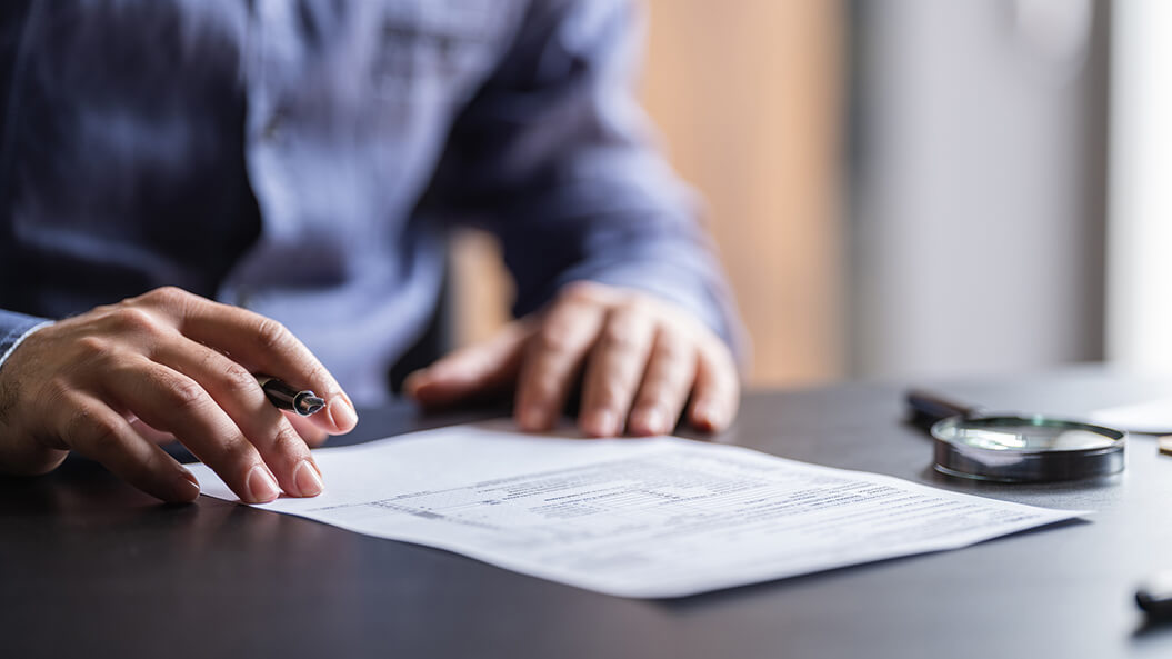 Close up of hands on papers, holding a pen