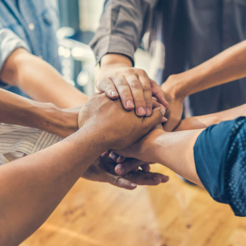 Several hands meeting in the middle of a circle after group therapy at a CCBHC