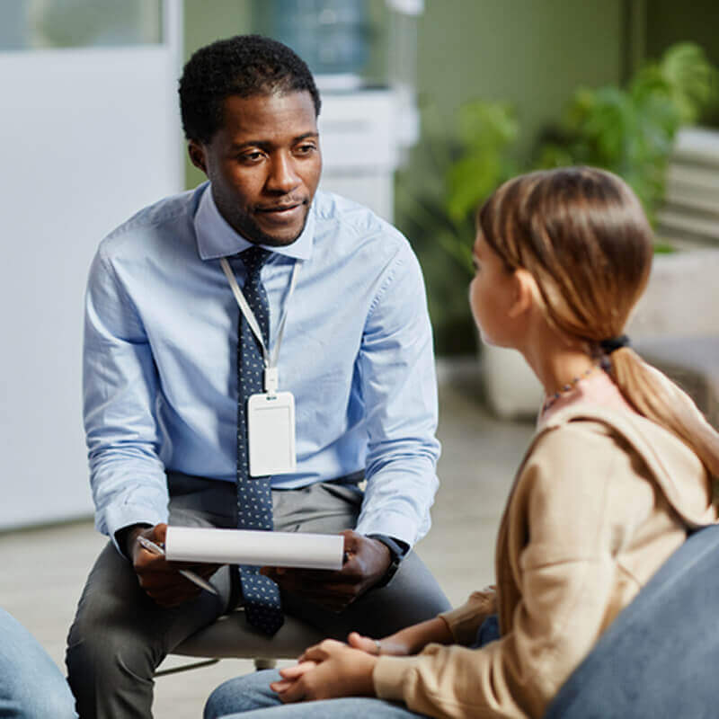 A man talking to a child and taking notes