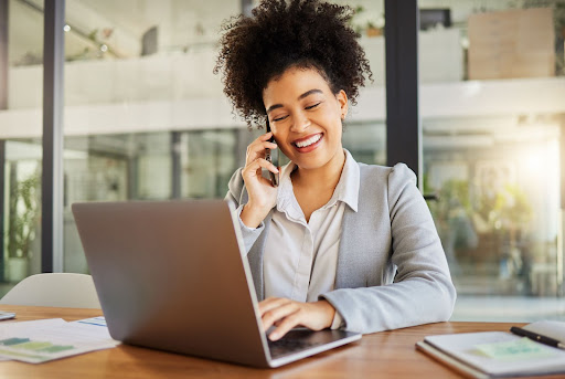 A woman on the phone and typing on a laptop