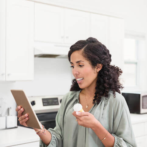 A woman holding a pill bottle and holding a tablet