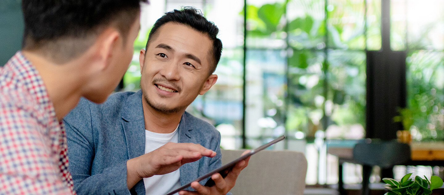 A man holding a tablet interacting with another individual