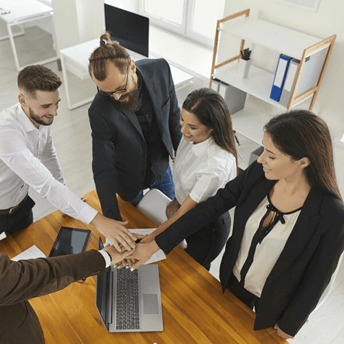 A group of business professionals joining hands in the middle of a circle