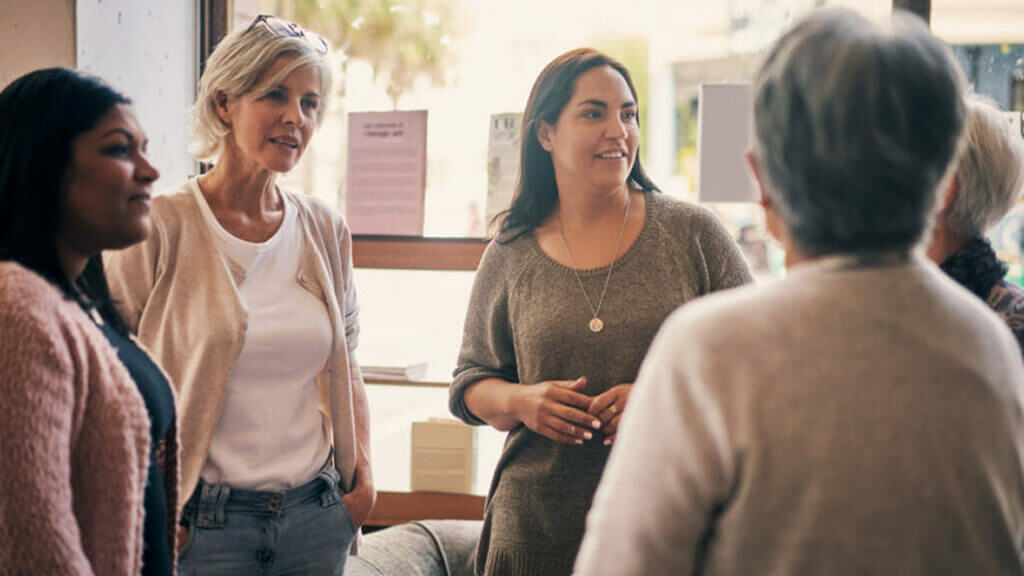 5 women standing in a circle and having a conversation about individuals with developmental disabilities..