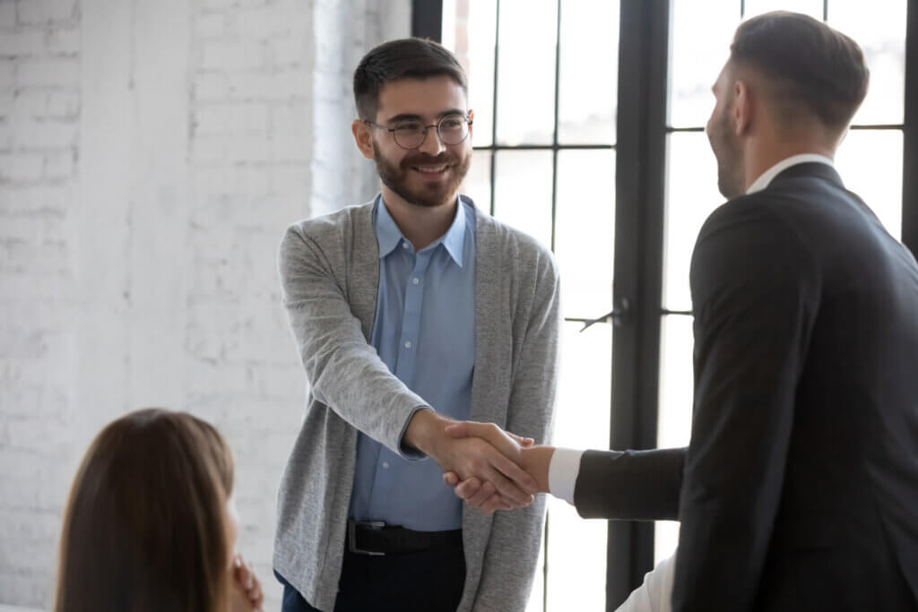 Two men shaking hands over deal made choosing Qualifacts EHR Platform for Mental Health