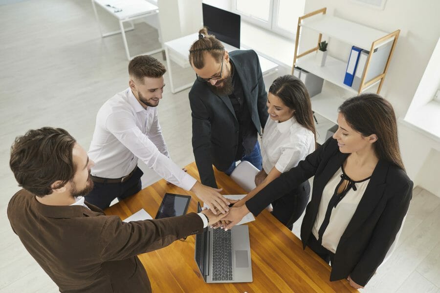 A group of business professionals joining hands in the middle of a circle