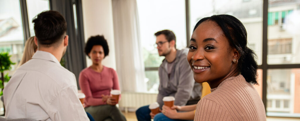 Diverse group of people sitting in circle in group therapy session.