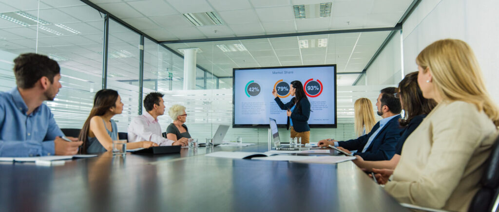 healthcare providers discussing clinical outcomes in a conference room with data charts on the big screen television.