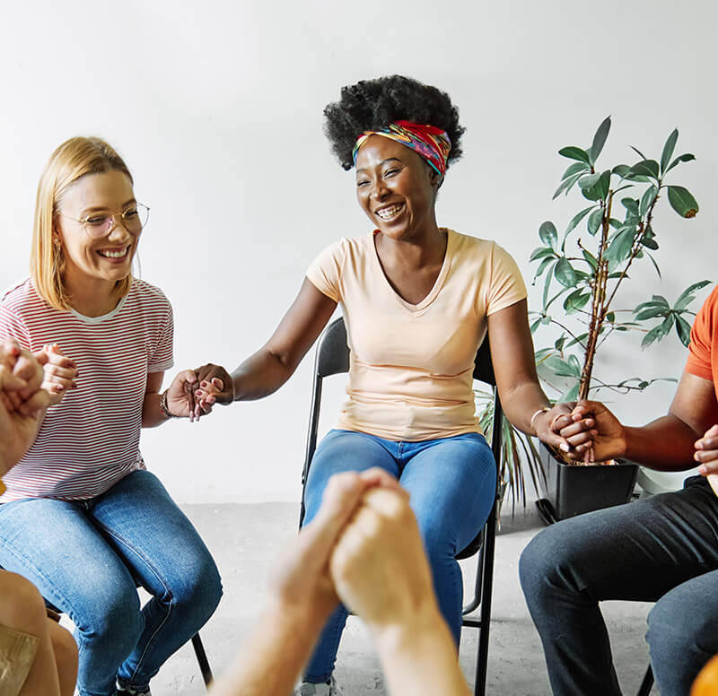 group therapy session with the participants holding hands