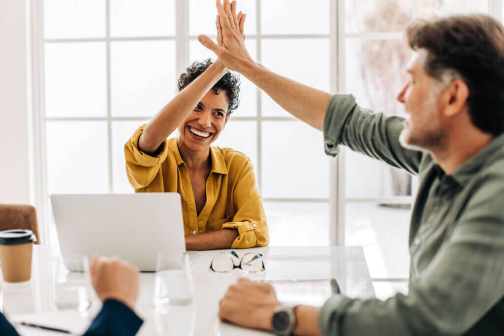 woman sitting in front of a laptop giving a high five to a man